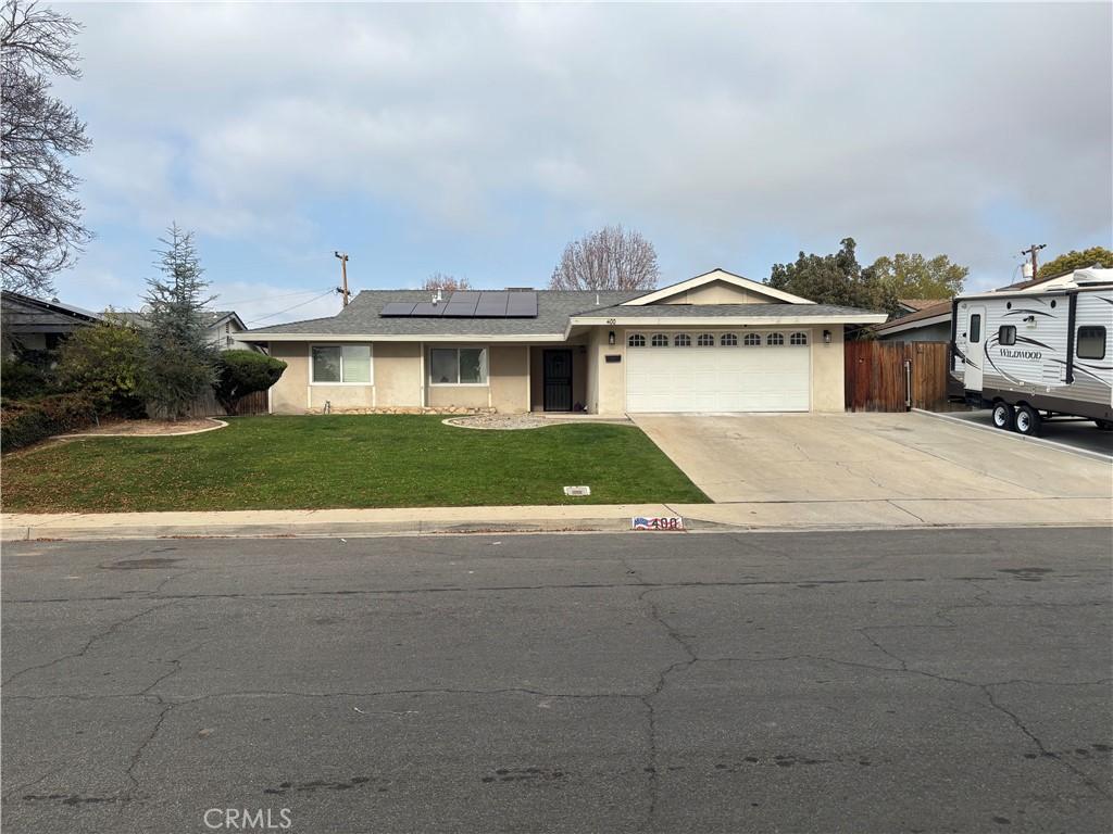 ranch-style house with a garage, a front lawn, and solar panels