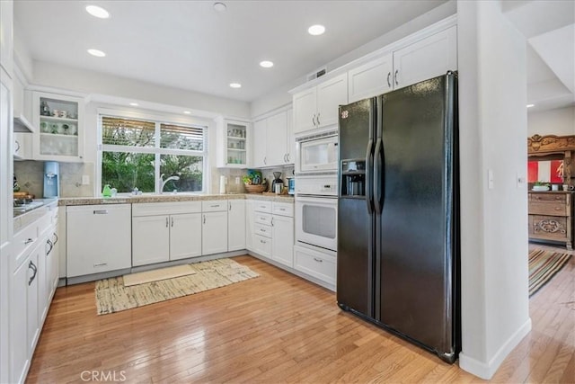 kitchen with white appliances, light hardwood / wood-style floors, decorative backsplash, and white cabinets