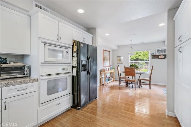 kitchen featuring pendant lighting, white cabinets, white appliances, and light hardwood / wood-style flooring