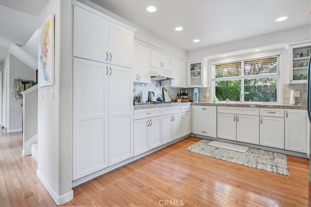 kitchen with decorative backsplash, white dishwasher, light hardwood / wood-style flooring, and white cabinets