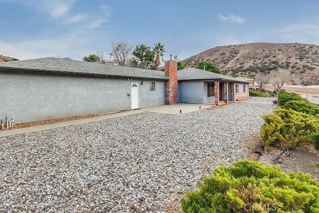 rear view of house with a mountain view and a patio area