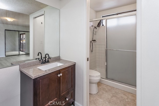 bathroom with tile patterned floors, toilet, a textured ceiling, vanity, and a shower with door