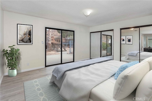 bedroom featuring access to exterior, two closets, light hardwood / wood-style flooring, and a textured ceiling