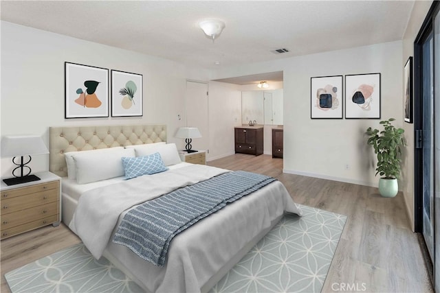 bedroom with ensuite bathroom, a textured ceiling, and light hardwood / wood-style floors