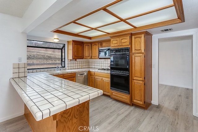 kitchen with stainless steel appliances, light hardwood / wood-style flooring, tile countertops, and kitchen peninsula