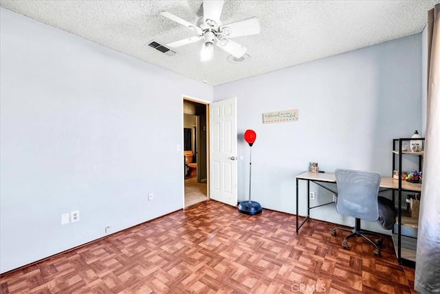 unfurnished office featuring parquet floors, a textured ceiling, and ceiling fan