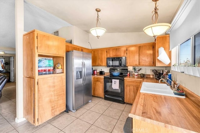 kitchen with light tile patterned floors, sink, hanging light fixtures, and black appliances