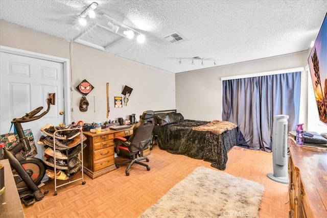 bedroom featuring light parquet flooring, track lighting, and a textured ceiling