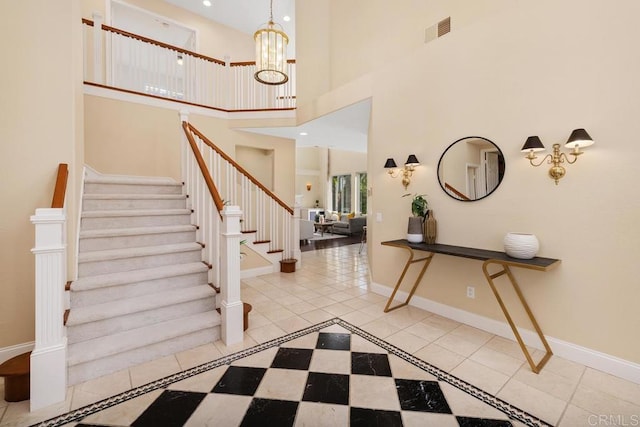 tiled entryway featuring a chandelier and a high ceiling