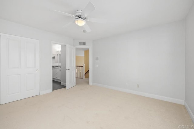 unfurnished bedroom with ceiling fan, light colored carpet, and ensuite bath