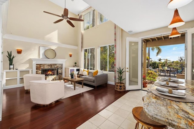 tiled living room with a towering ceiling, ornamental molding, a premium fireplace, and a wealth of natural light