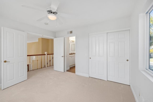 unfurnished bedroom featuring ceiling fan, light colored carpet, ensuite bath, and a closet