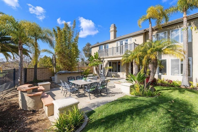 rear view of house with a balcony, a yard, and a patio area