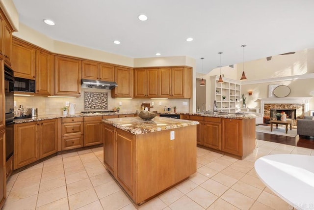 kitchen with pendant lighting, backsplash, a center island, kitchen peninsula, and light stone countertops