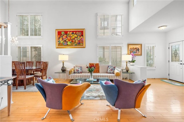 living room with a high ceiling, a notable chandelier, and light wood-style floors