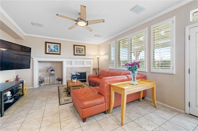 living area featuring a ceiling fan, a fireplace, crown molding, light tile patterned floors, and baseboards