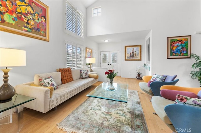 living area featuring french doors, a towering ceiling, and wood finished floors