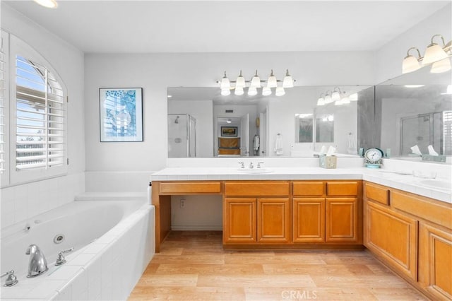 bathroom featuring plus walk in shower, wood-type flooring, and vanity