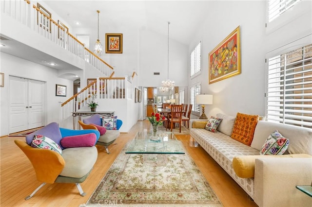 living room with light hardwood / wood-style floors, a chandelier, and a high ceiling