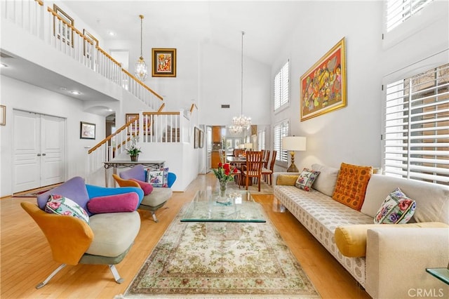 living area featuring stairway, a notable chandelier, a high ceiling, and wood finished floors