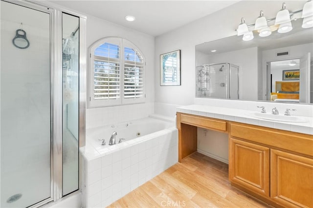 bathroom featuring hardwood / wood-style flooring, vanity, and shower with separate bathtub