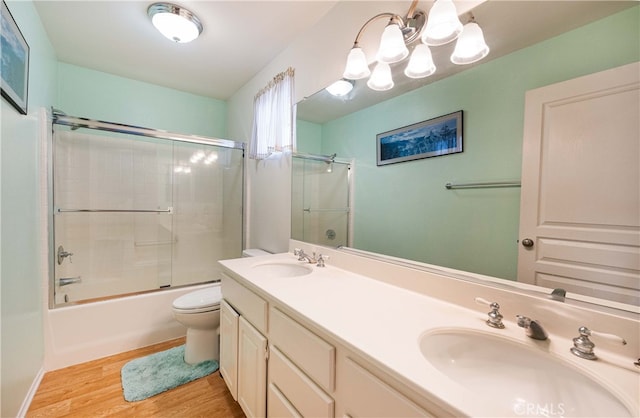 full bathroom with a sink, toilet, wood finished floors, and double vanity