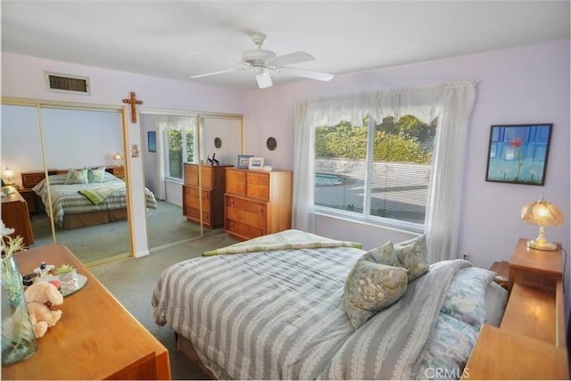 carpeted bedroom with multiple closets and ceiling fan