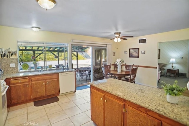 kitchen with sink, light tile patterned floors, dishwasher, light stone countertops, and stove