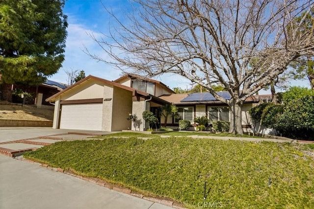 view of front of property with a garage, a front lawn, and solar panels