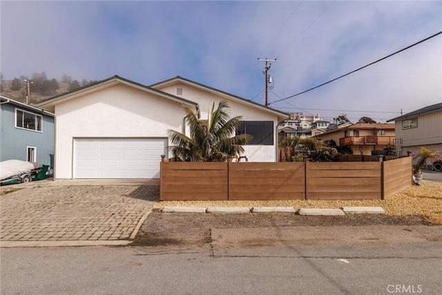 view of front of house featuring a garage, fence, decorative driveway, and stucco siding