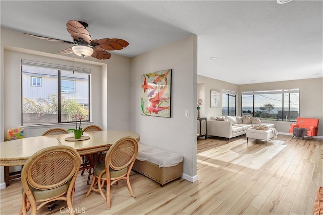 dining space with a ceiling fan, light wood-style flooring, and baseboards