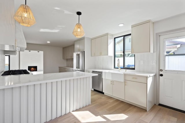 kitchen featuring hanging light fixtures, light hardwood / wood-style flooring, stainless steel appliances, and kitchen peninsula