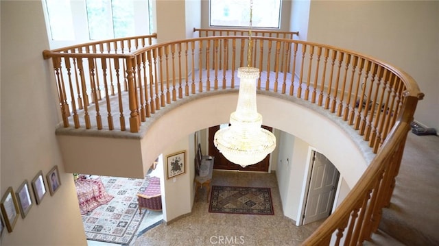 stairway with an inviting chandelier and a towering ceiling