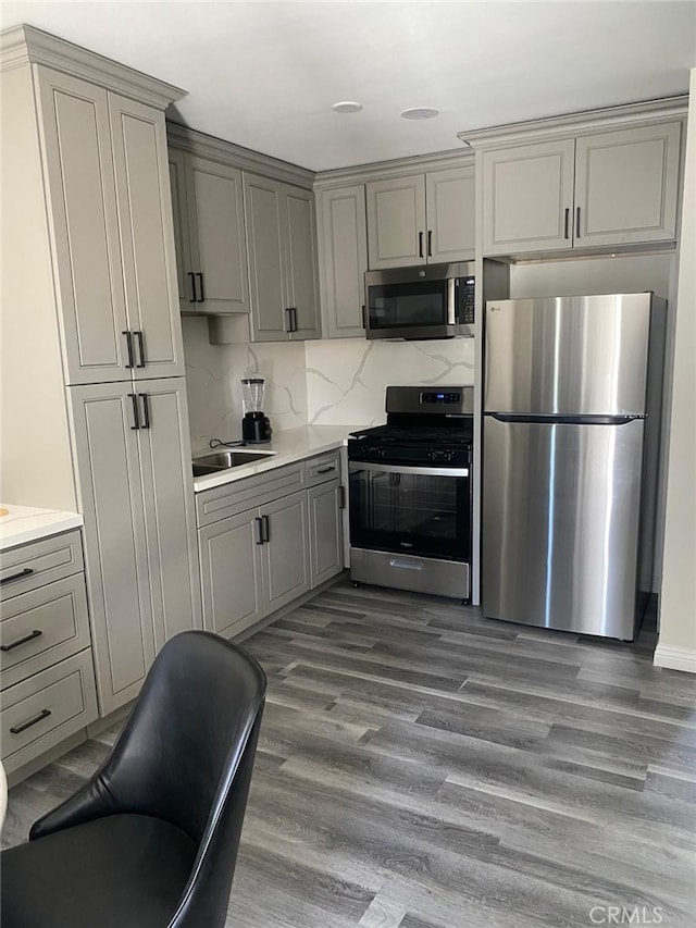 kitchen with dark wood-type flooring, gray cabinets, stainless steel appliances, and decorative backsplash