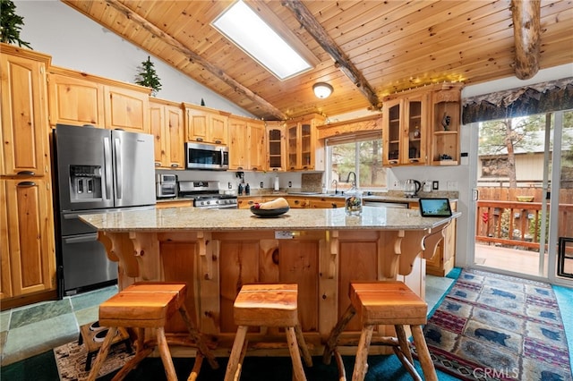 kitchen with wood ceiling, appliances with stainless steel finishes, a kitchen breakfast bar, a kitchen island, and light stone countertops