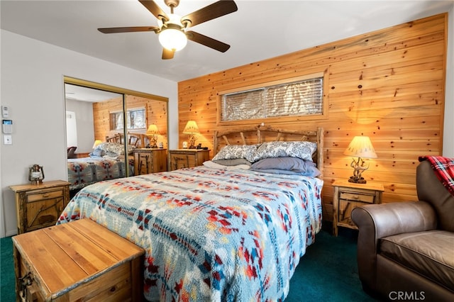 bedroom with ceiling fan, wooden walls, a closet, and dark colored carpet