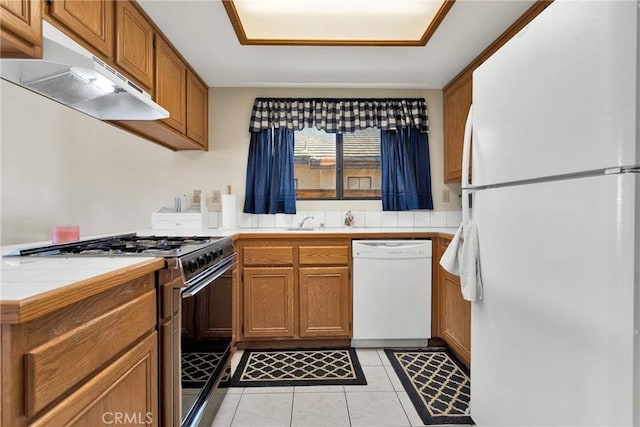 kitchen with light tile patterned floors, white appliances, tile countertops, and sink