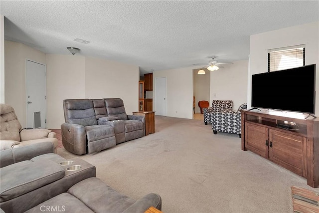 carpeted living room featuring ceiling fan and a textured ceiling