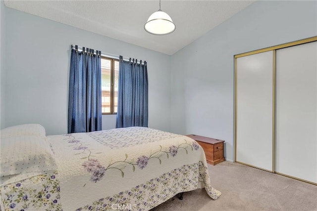 bedroom featuring light colored carpet, vaulted ceiling, and a closet