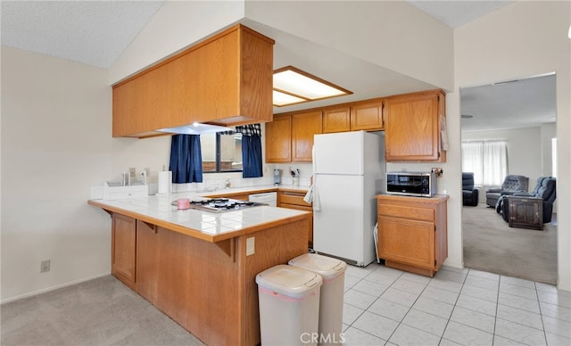 kitchen with lofted ceiling, tile countertops, light carpet, kitchen peninsula, and stainless steel appliances