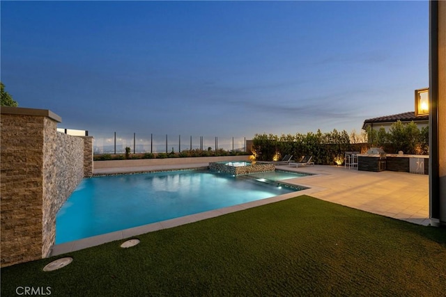 20436 W Liverpool Way, Porter Ranch, CA 91326 - pool at dusk featuring a pool with connected hot tub, a patio area, and an outdoor kitchen