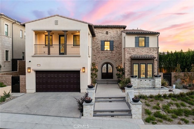 mediterranean / spanish house with a garage, a balcony, and french doors