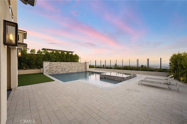 pool at dusk featuring a patio