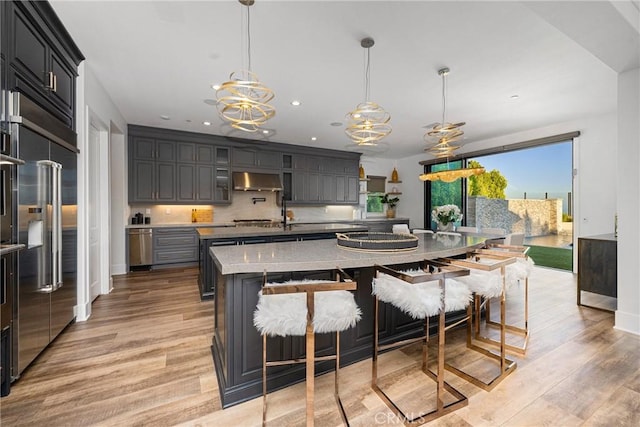20436 W Liverpool Way, Porter Ranch, CA 91326 - kitchen featuring an island with sink, extractor fan, stainless steel appliances, light wood-type flooring, and recessed lighting