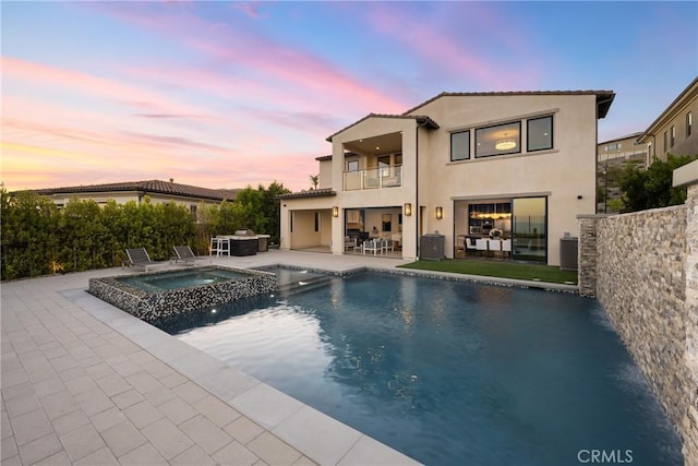 pool at dusk with central AC, a patio area, and an in ground hot tub