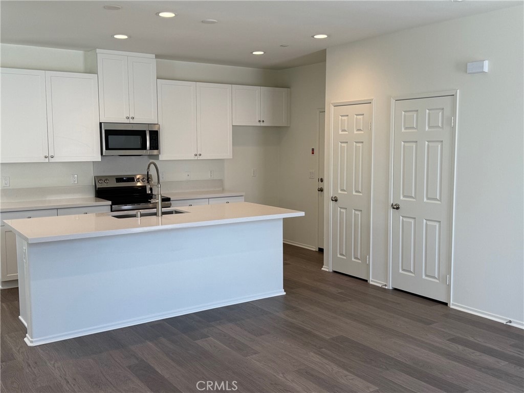 2255 Spring Meadow Ct, San Bernardino, CA 92346 - kitchen with appliances with stainless steel finishes, dark wood finished floors, white cabinetry, recessed lighting, and a center island with sink