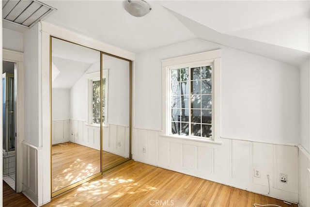 unfurnished bedroom featuring hardwood / wood-style flooring, a closet, and lofted ceiling