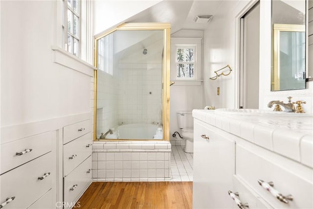 full bathroom featuring combined bath / shower with glass door, vanity, toilet, and hardwood / wood-style floors