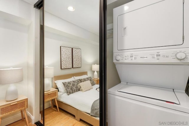 washroom featuring stacked washer and clothes dryer and light hardwood / wood-style floors