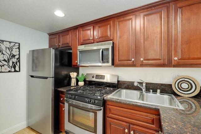 kitchen with stainless steel appliances, sink, and dark stone counters